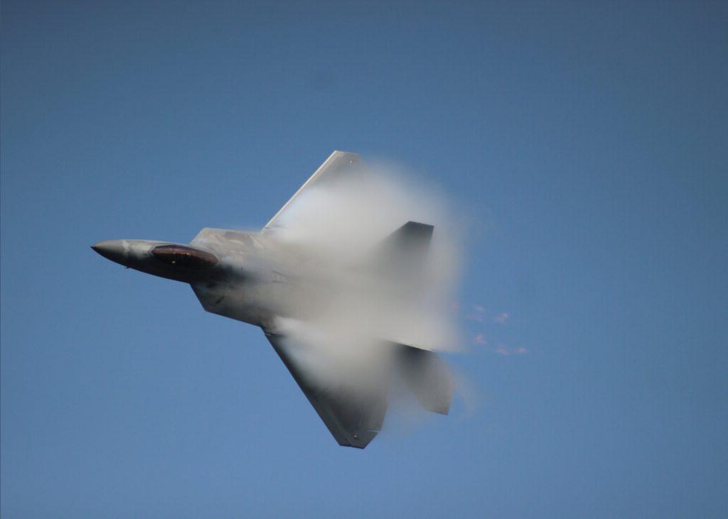 Photo of a fighter jet flying in the blue sky, blurred by motion