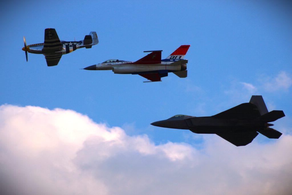 three airplanes flying together with blue sky and clouds in background